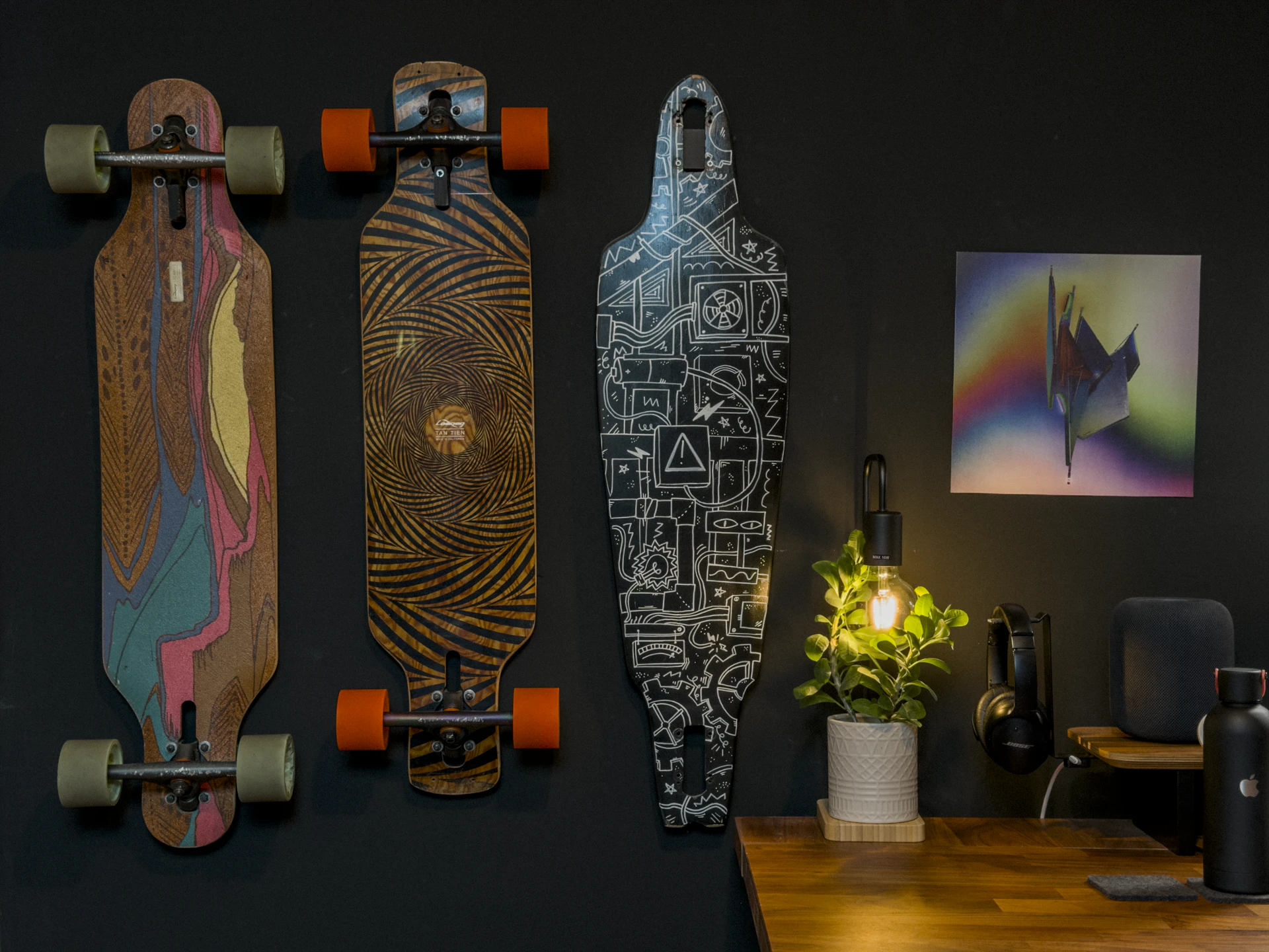 Three longboards mounted on a dark wall above a desk: a Loaded Icarus, a Loaded Tan Tien and a Globe Prowler