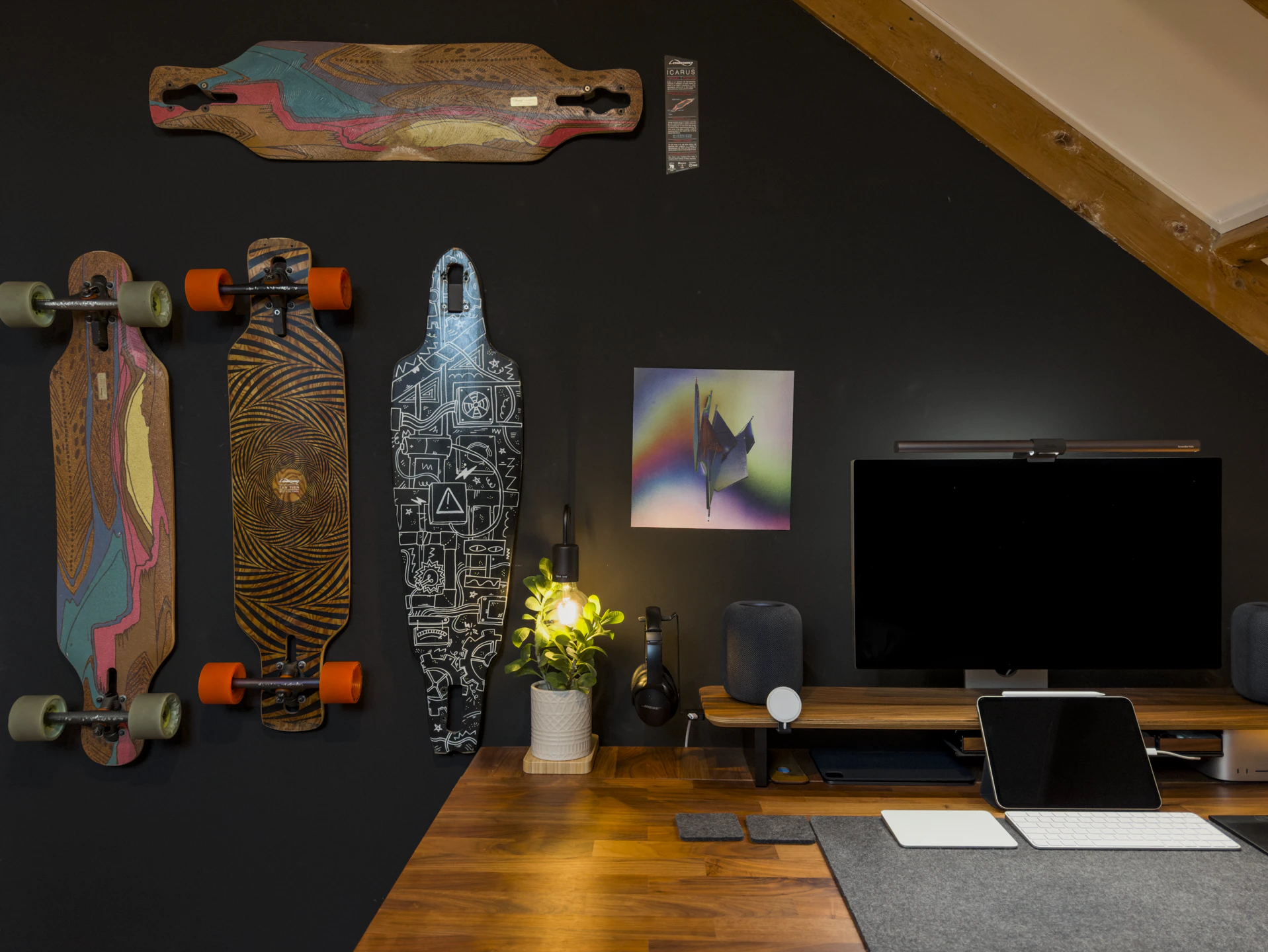 Wider view of the desk setup with the three longboards and a fourth deck on the wall